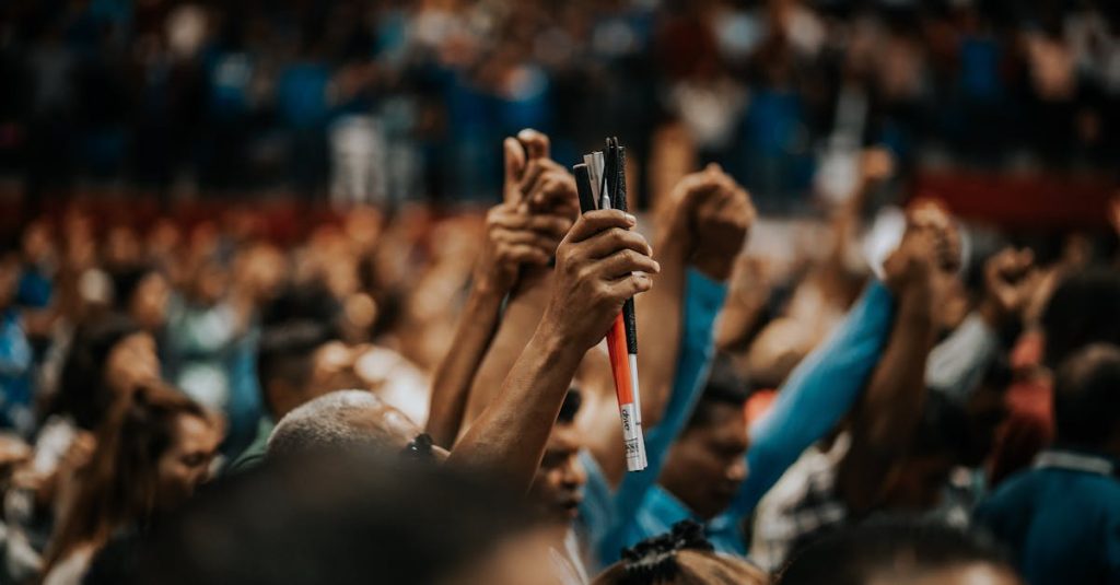 Energetic crowd with raised hands in a vibrant indoor gathering, symbolizing unity.